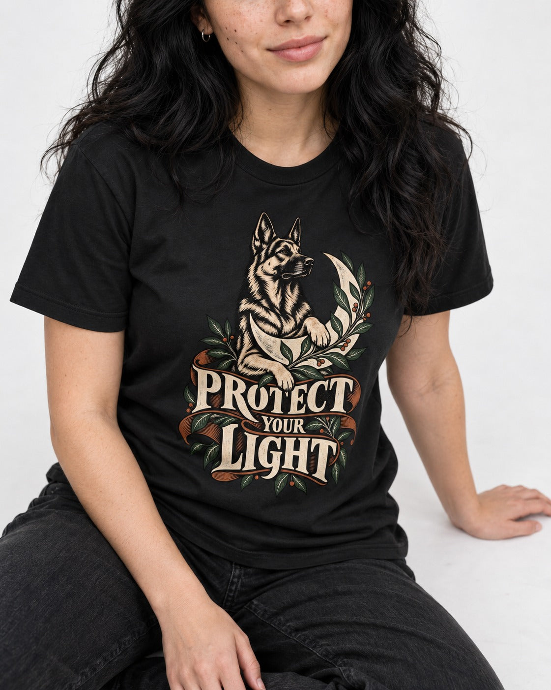 Protect Your Light Moon Botanical German Shepherd Dog Graphic T-Shirt in Black, worn by a seated model