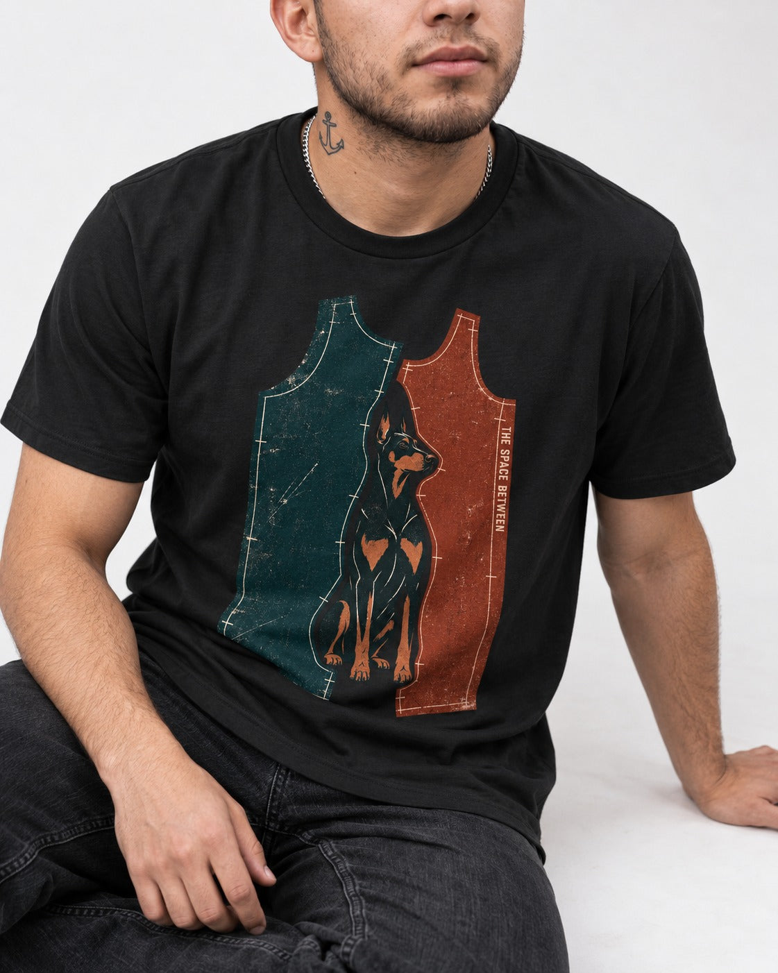 Doberman The Space Between Pattern Pieces Graphic T-Shirt in Black, worn by a seated model