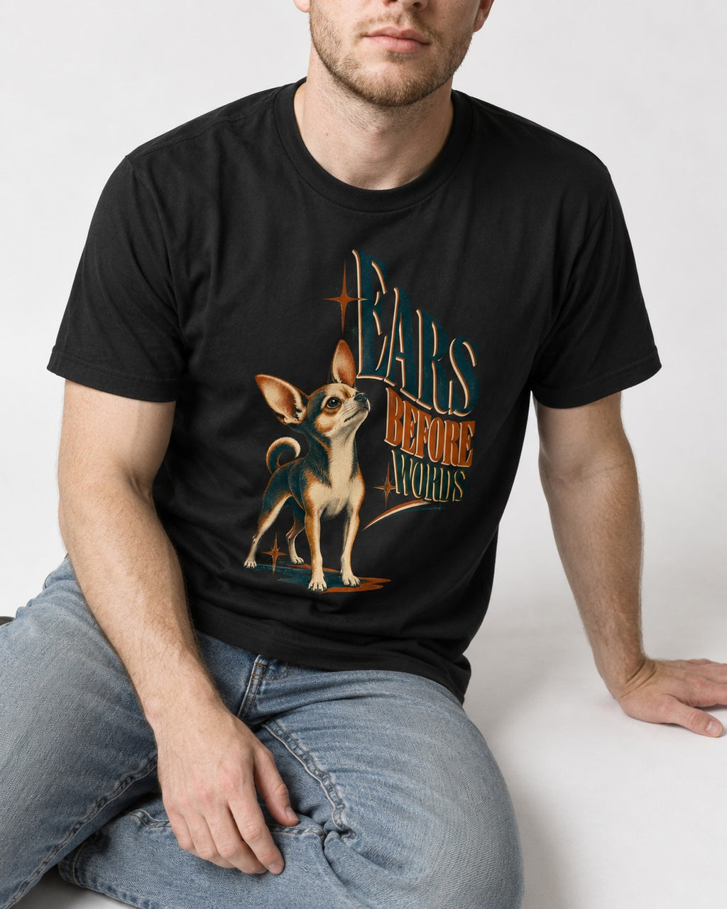 Chihuahua Ears Before Words Retro Typography T-Shirt in Black, worn by a seated model