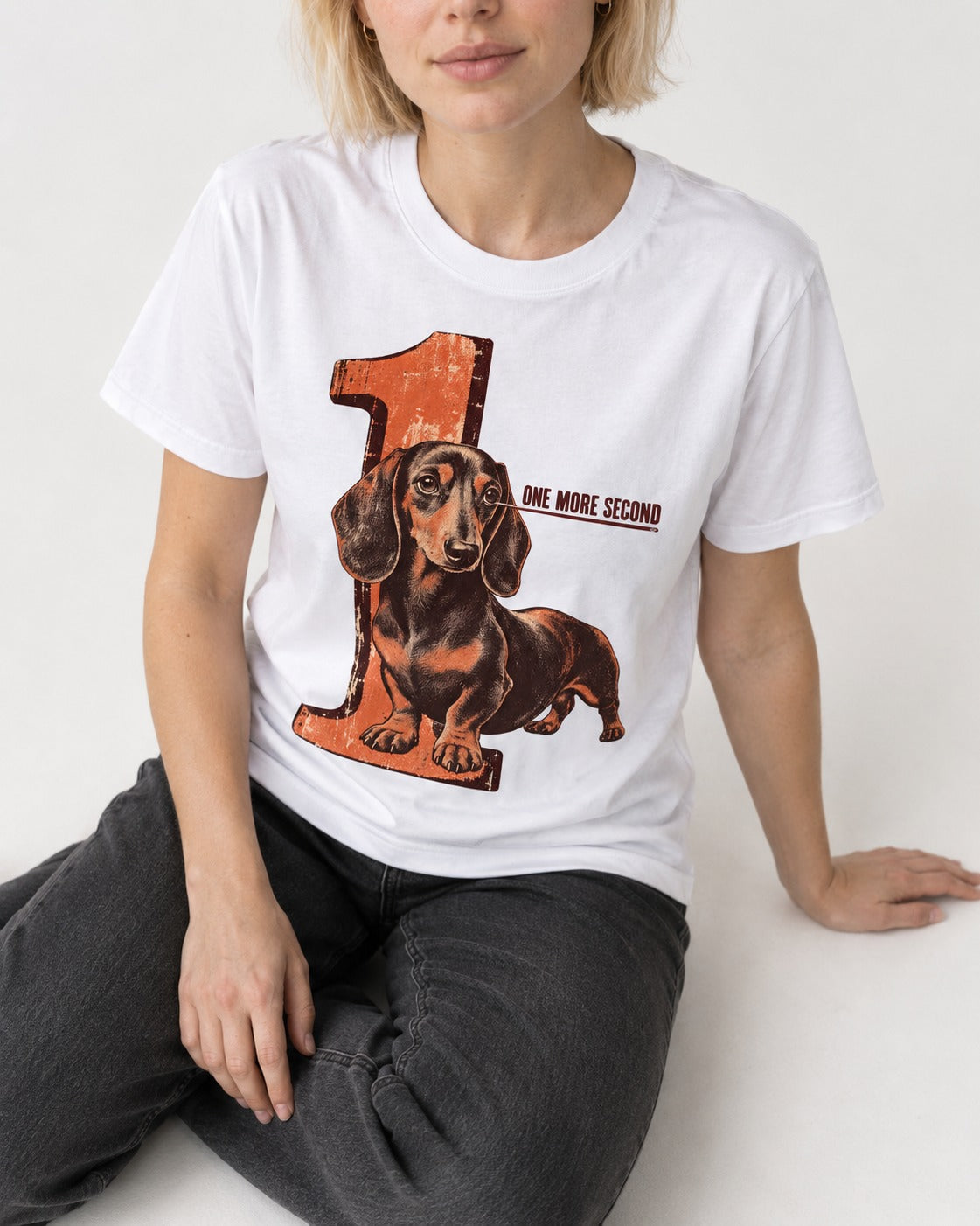One More Second Dachshund T-Shirt in White, worn by a seated model