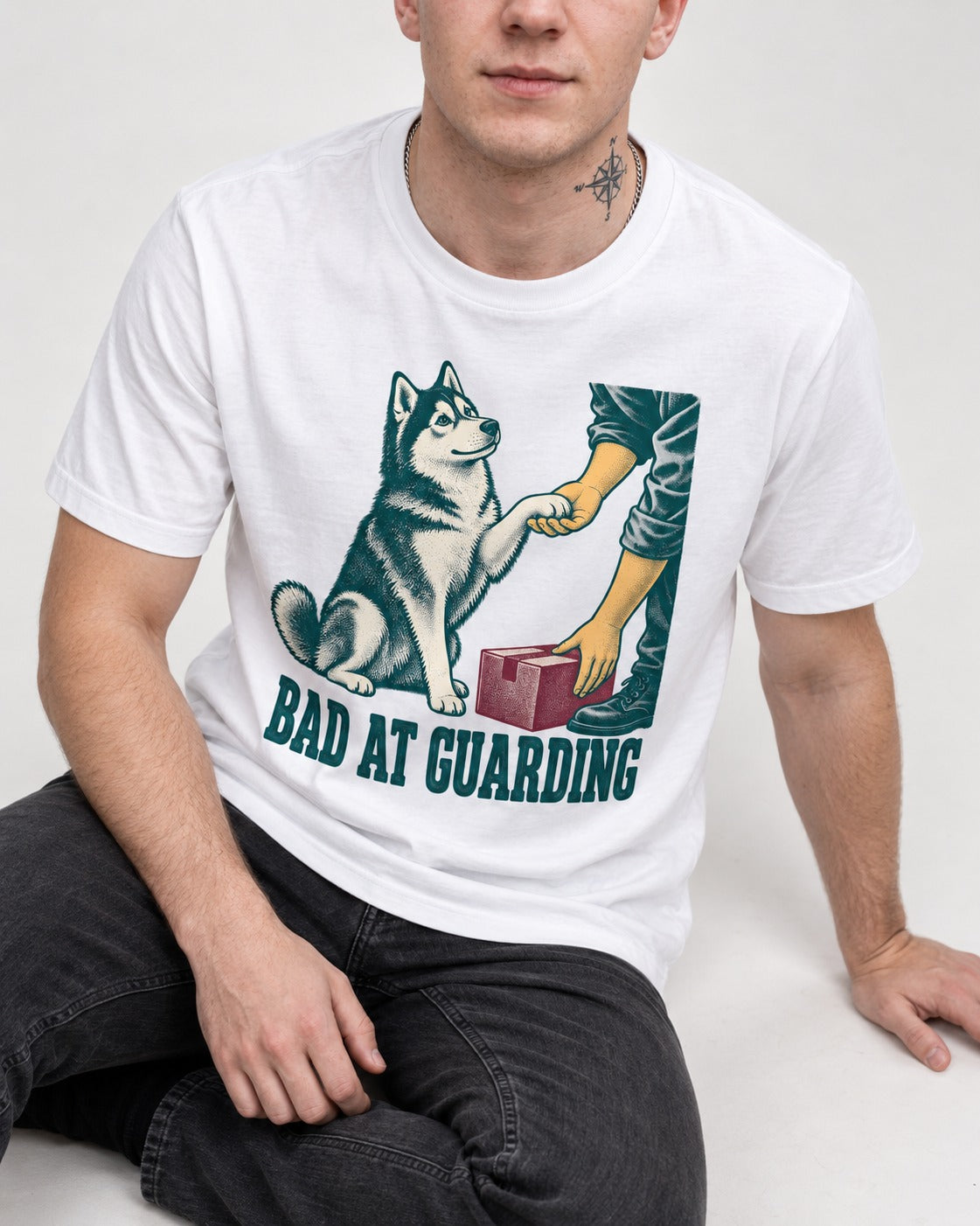 Husky's Bad at Guarding T-Shirt in White, worn by a seated model
