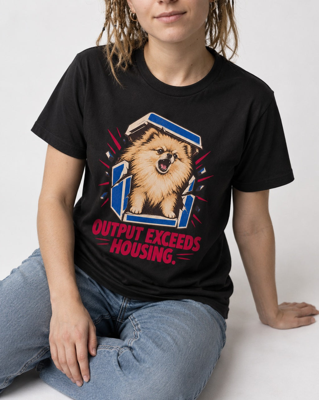 Pomeranian Output Exceeds Housing Bark Compression Graphic T-Shirt in Black, worn by a seated model