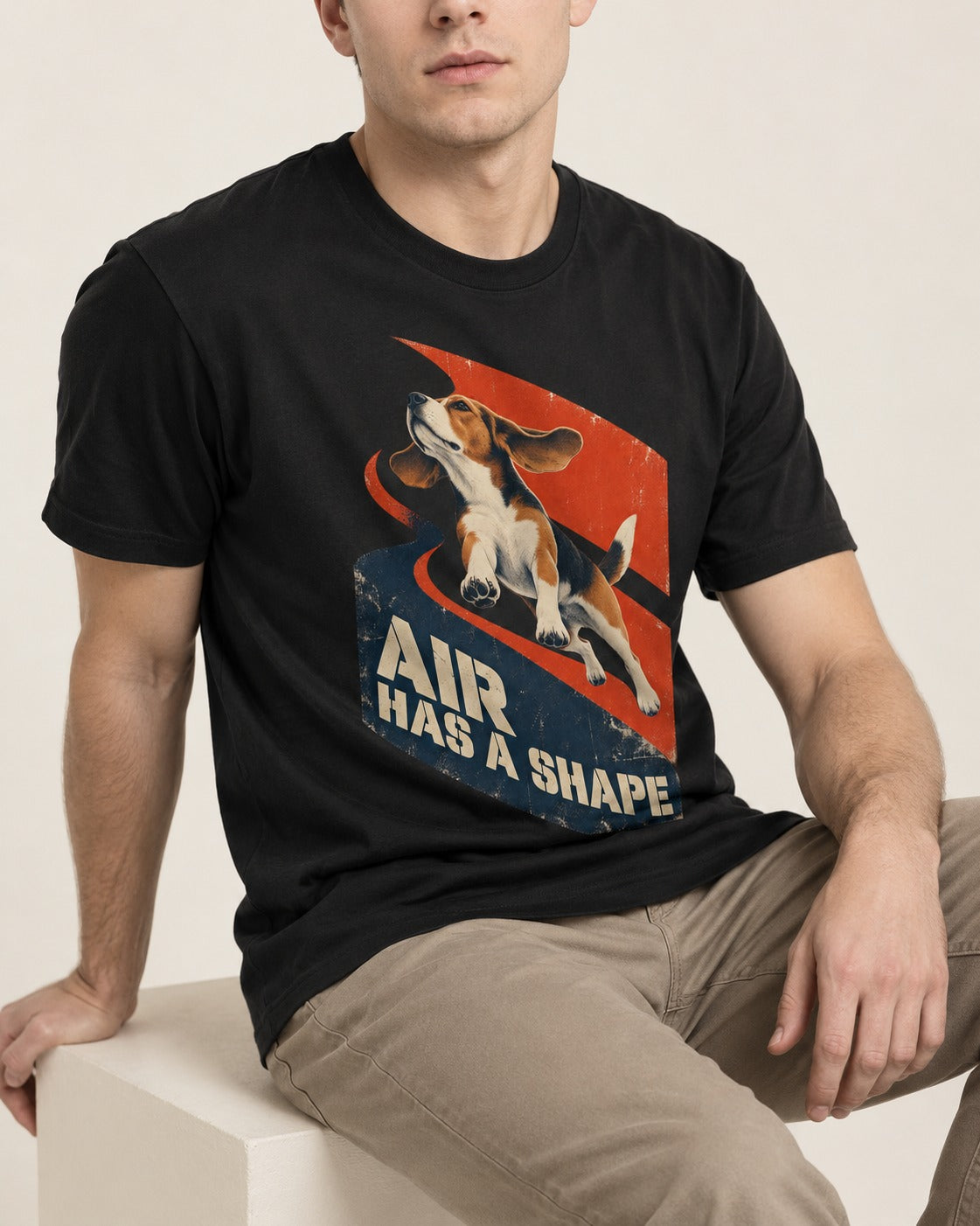 Air Has A Shape Beagle Jumping Graphic T-Shirt in Black, worn by a seated model