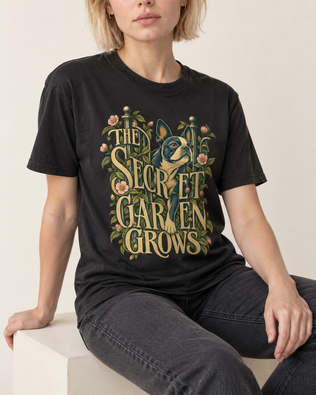 The Secret Garden Grows Boston Terrier T-Shirt in Black, worn by a seated model