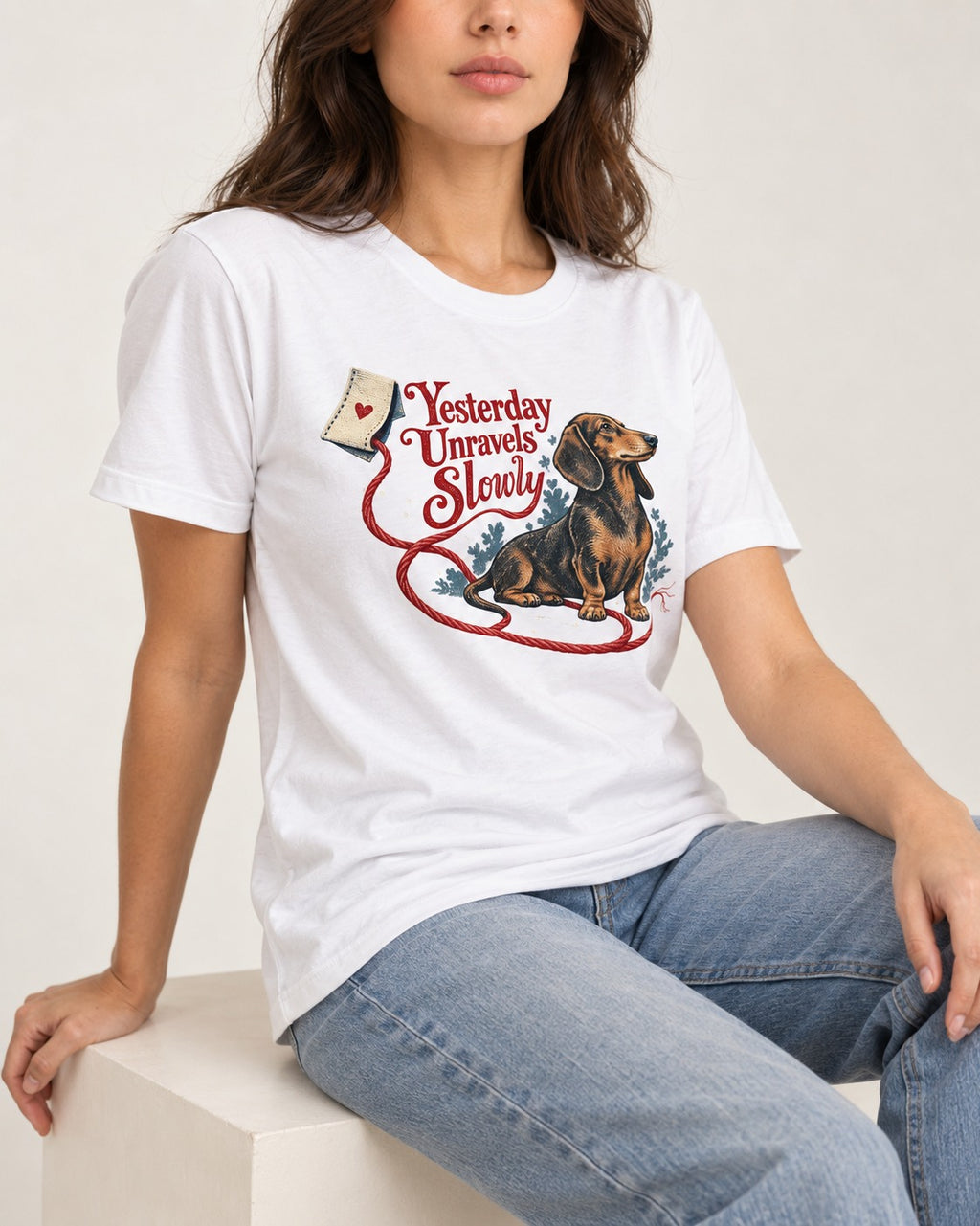 Yesterday Unravels Slowly with Dachshund T-Shirt in White, worn by a seated model