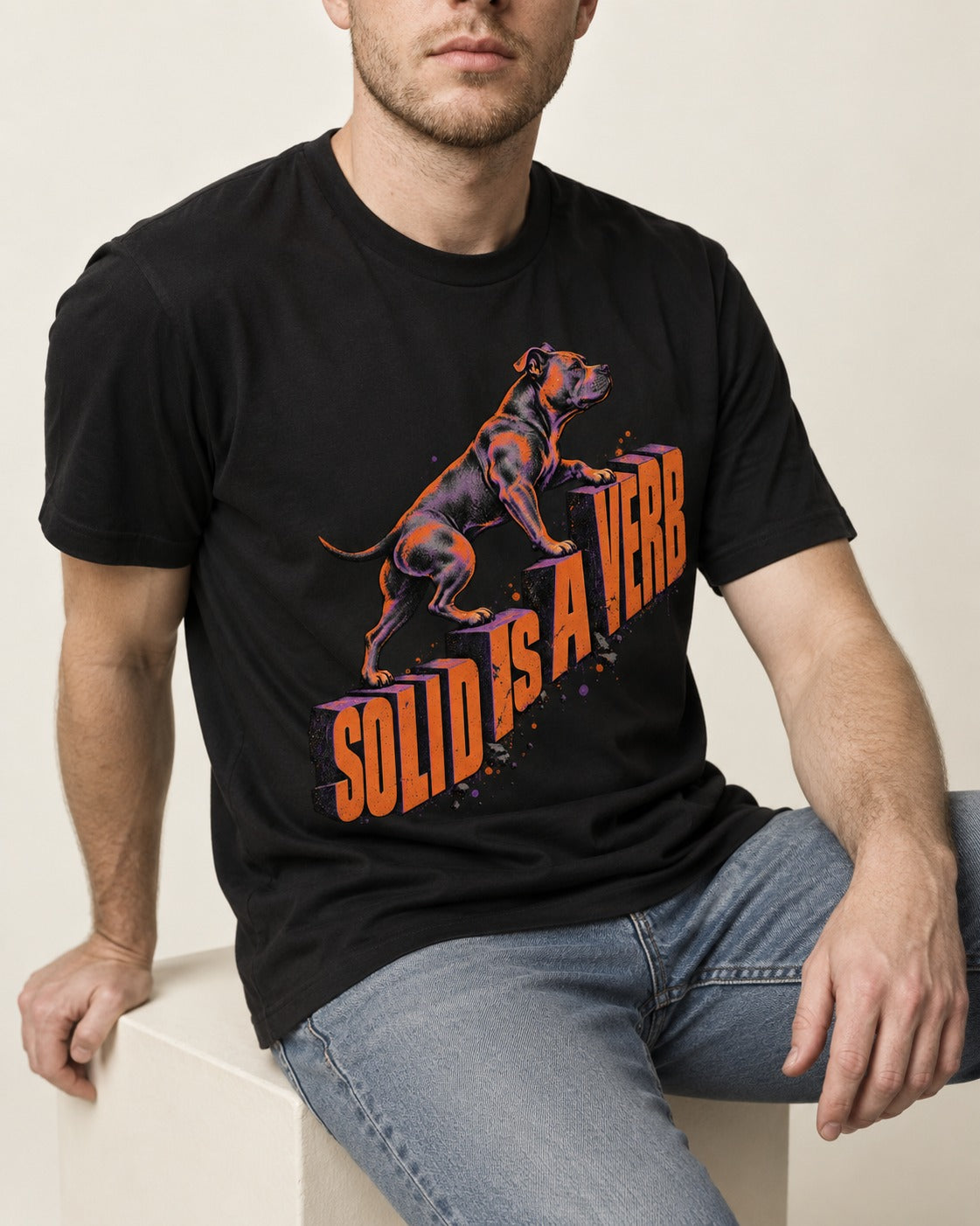 Pitbull Solid Is a Verb Step Type Graphic T-Shirt in Black, worn by a seated model