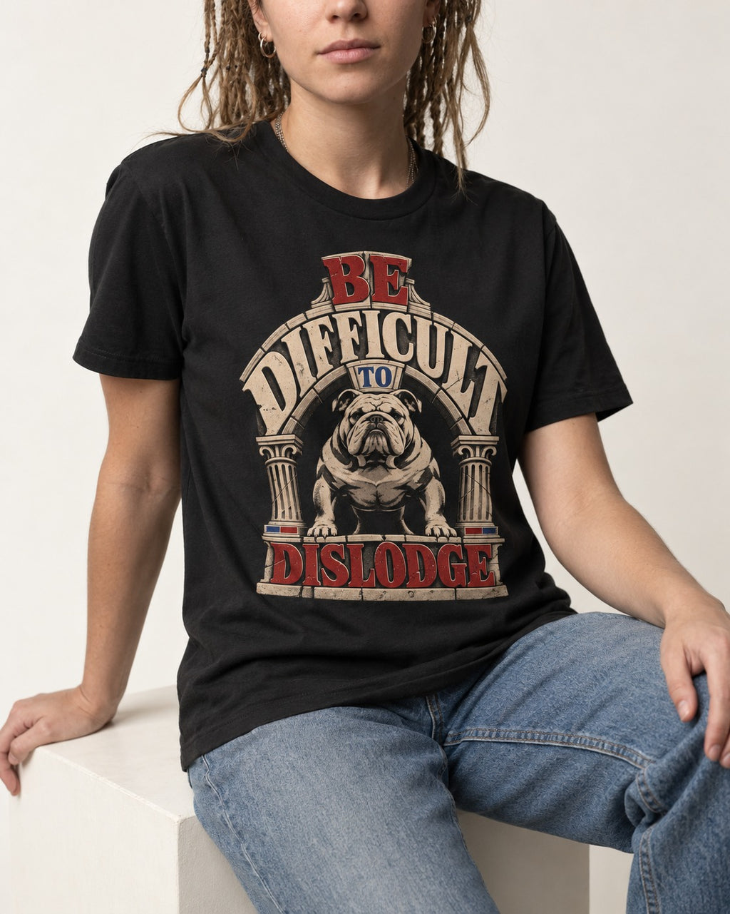 English Bulldog Be Difficult to Dislodge Stone Arch Graphic T-Shirt in Black, worn by a seated model