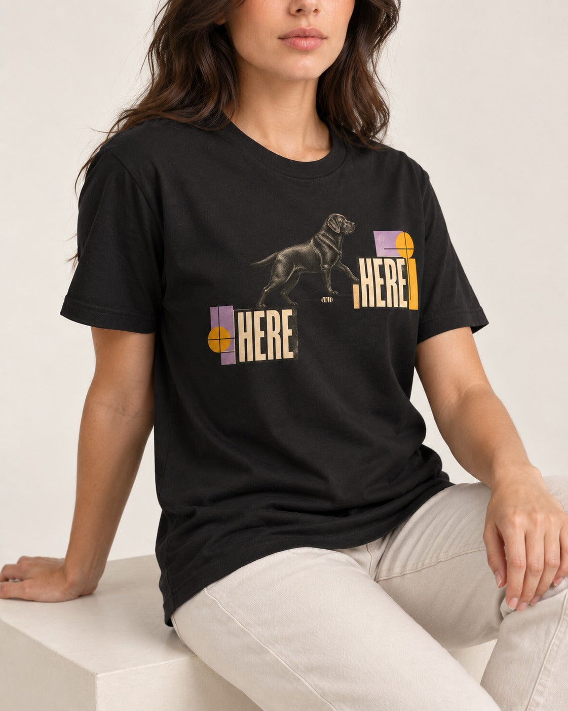 Here and Here Stepping Labrador Retriever Graphic T-Shirt in Black, worn by a seated model