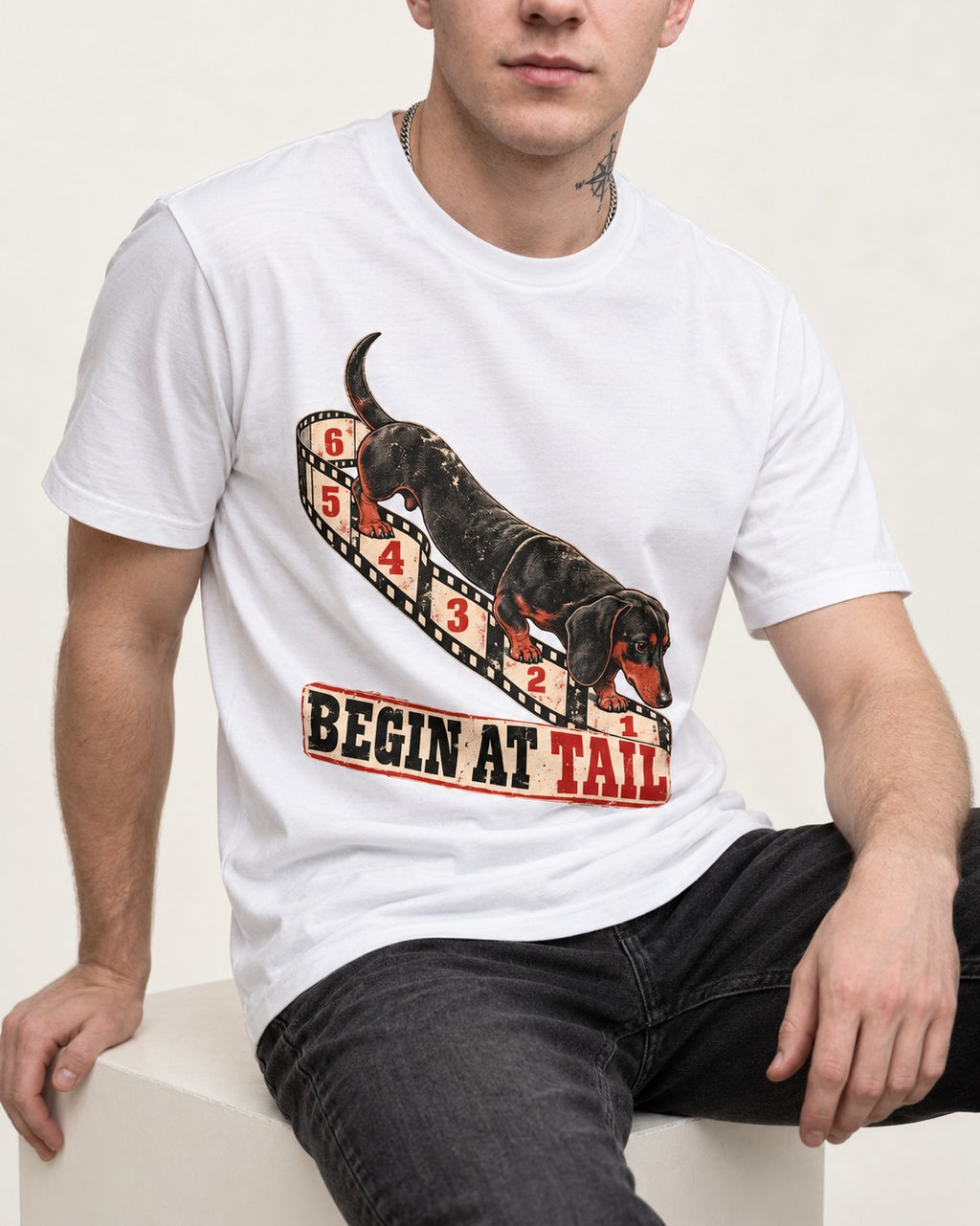 Begin at Tail Dachshund T-Shirt in White, worn by a seated model
