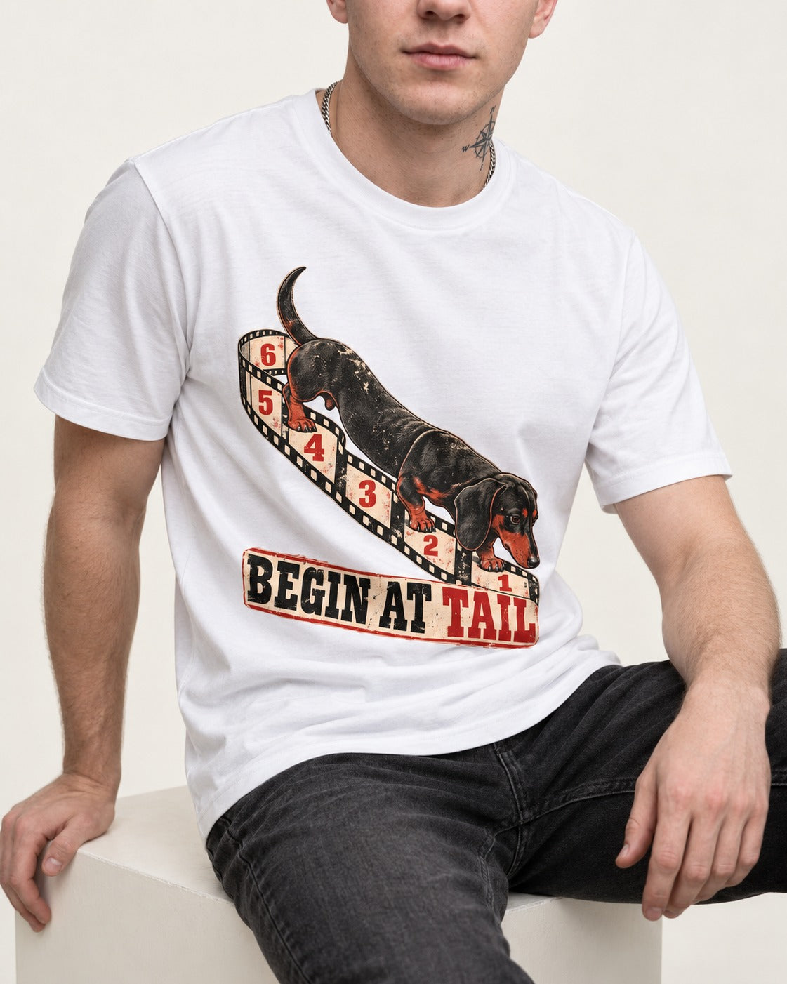 Begin at Tail Dachshund T-Shirt in White, worn by a seated model
