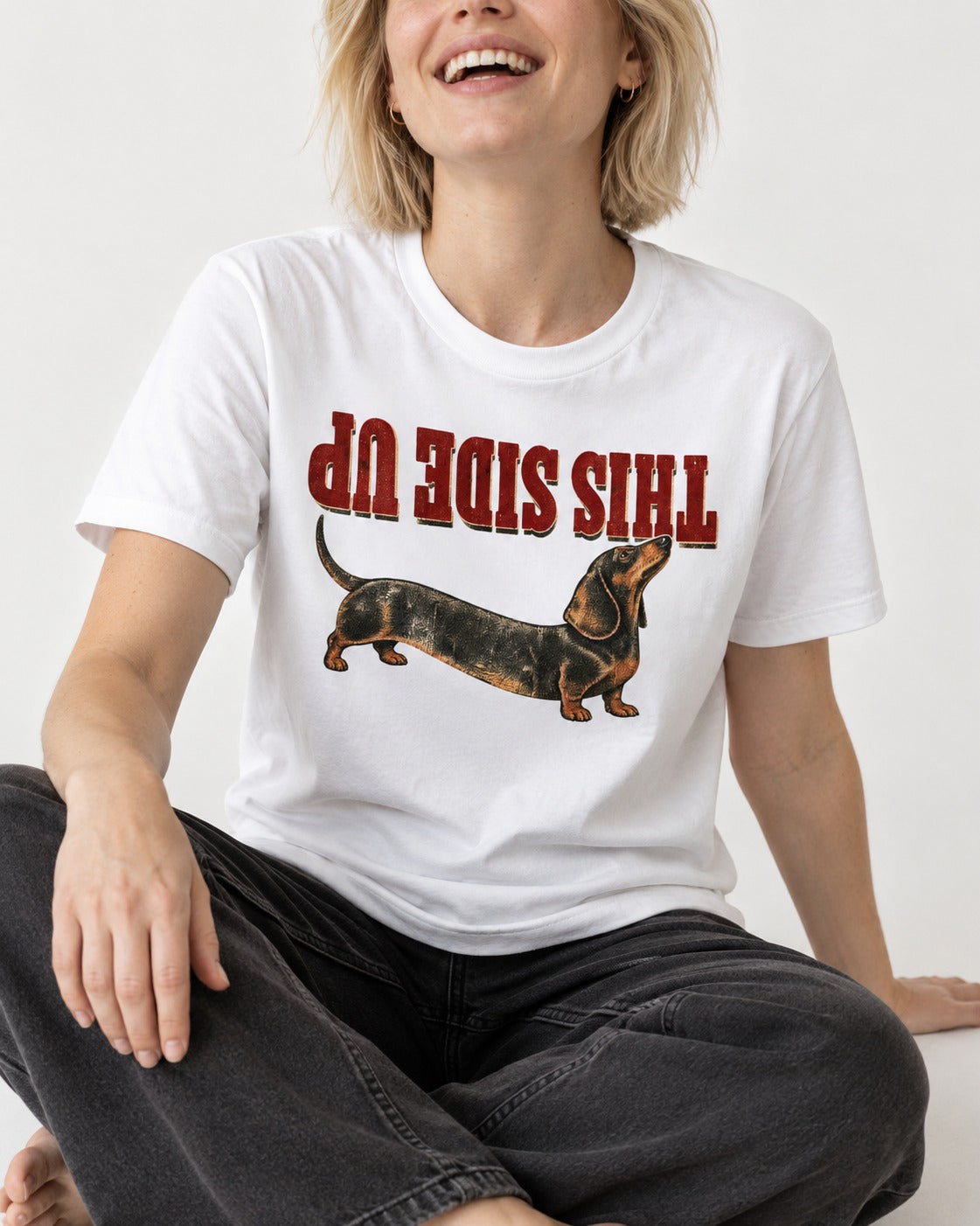 This Side Up Dachshund T-Shirt in White, worn by a seated model