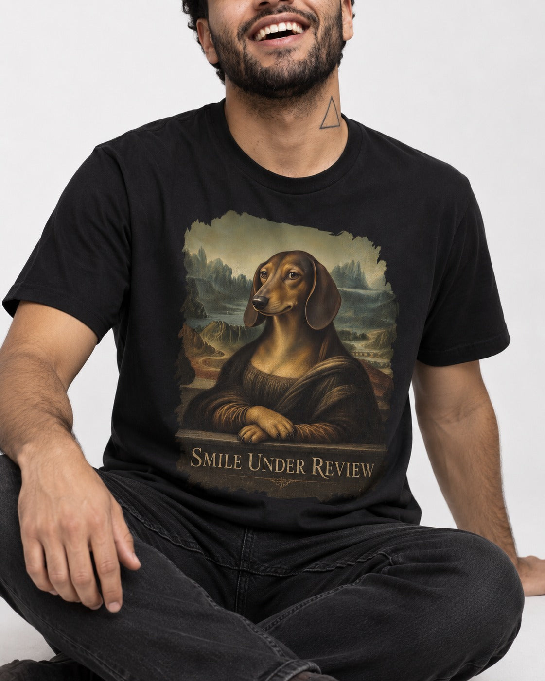 Dachshund Smile Under Review Mona Lisa Graphic T-Shirt in Black, worn by a seated model
