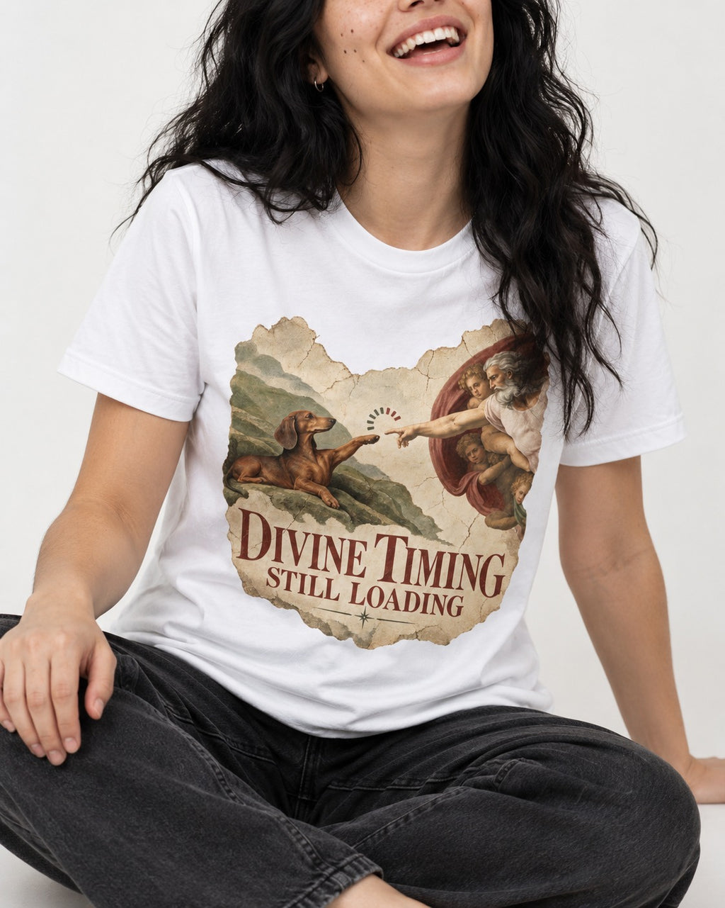 Dachshund's Divine Timing T-Shirt in White, worn by a seated model