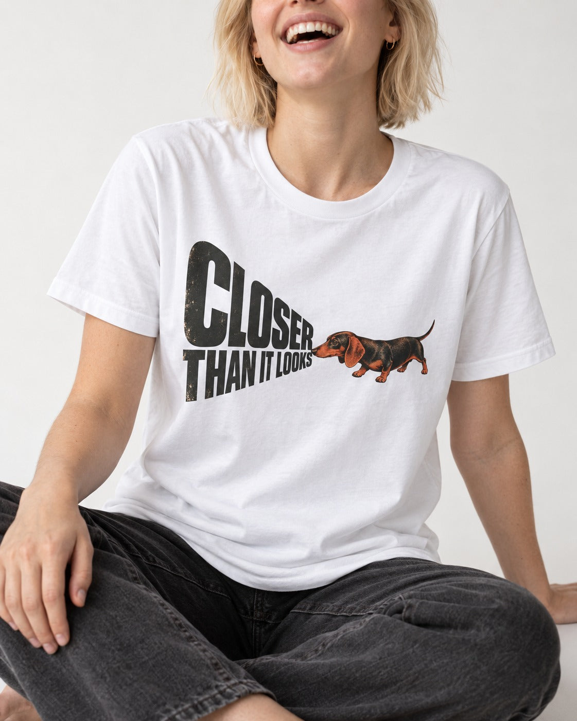 Dachshund Closer Than It Looks T-Shirt in White, worn by a seated model