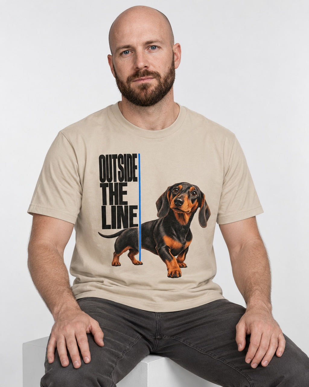 Dachshund Outside the Line T-Shirt in Sand, worn by a seated model