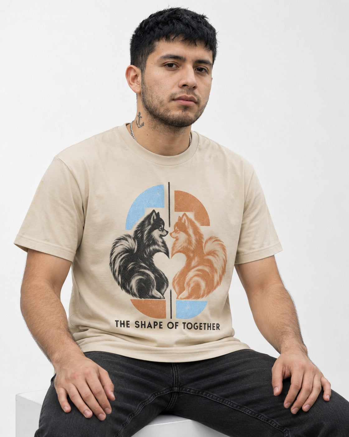 Pomeranian The Shape of Together T-Shirt in Sand, worn by a seated model