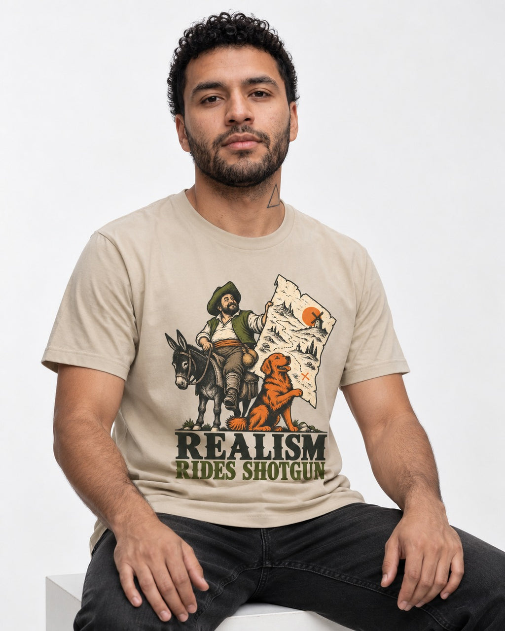 Realism Rides Shotgun with Golden Retriever T-Shirt in Sand, worn by a seated model