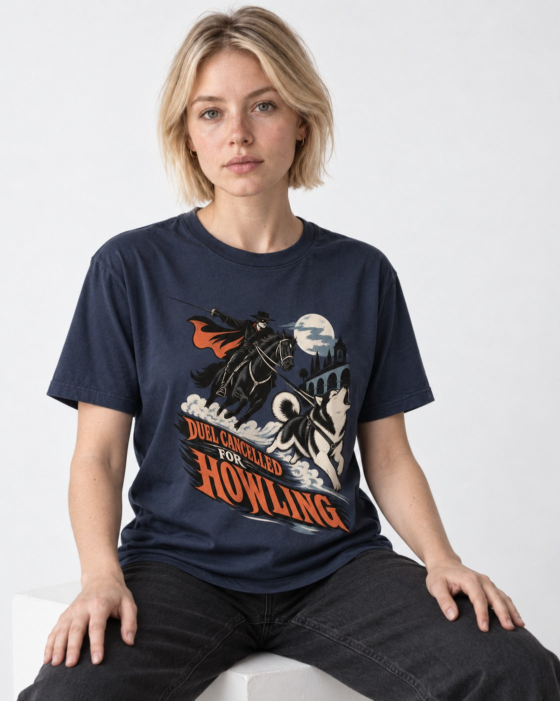 Husky Duel Cancelled for Howling Masked Rider Graphic T-Shirt in Navy, worn by a seated model