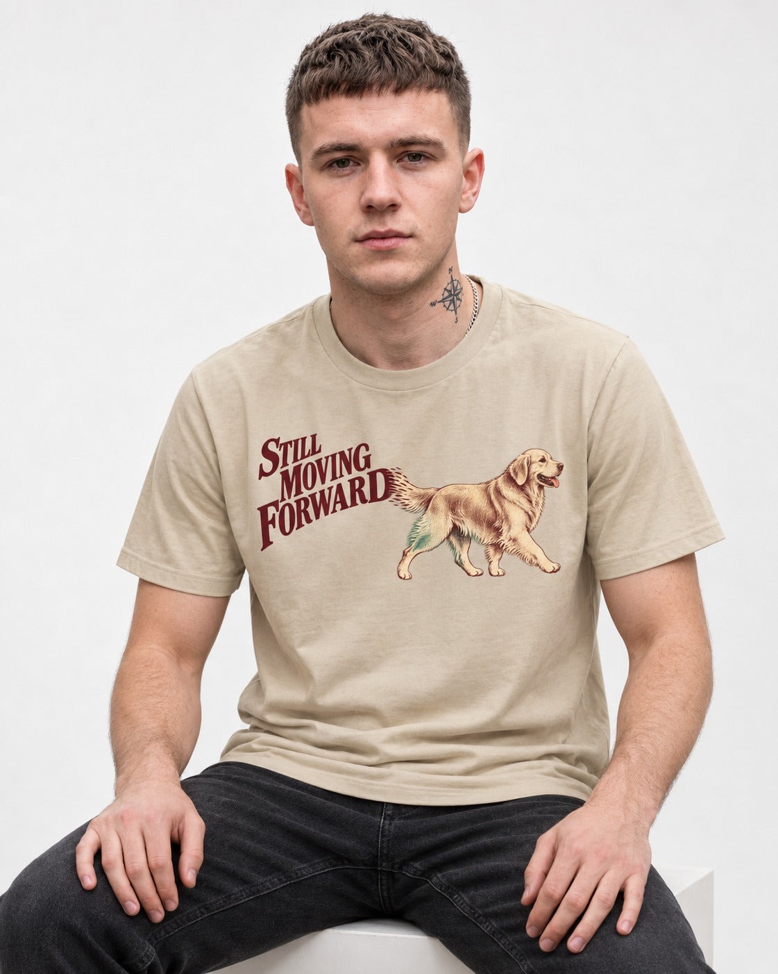 Golden Retriever Still Moving Forward T-Shirt in Sand, worn by a seated model