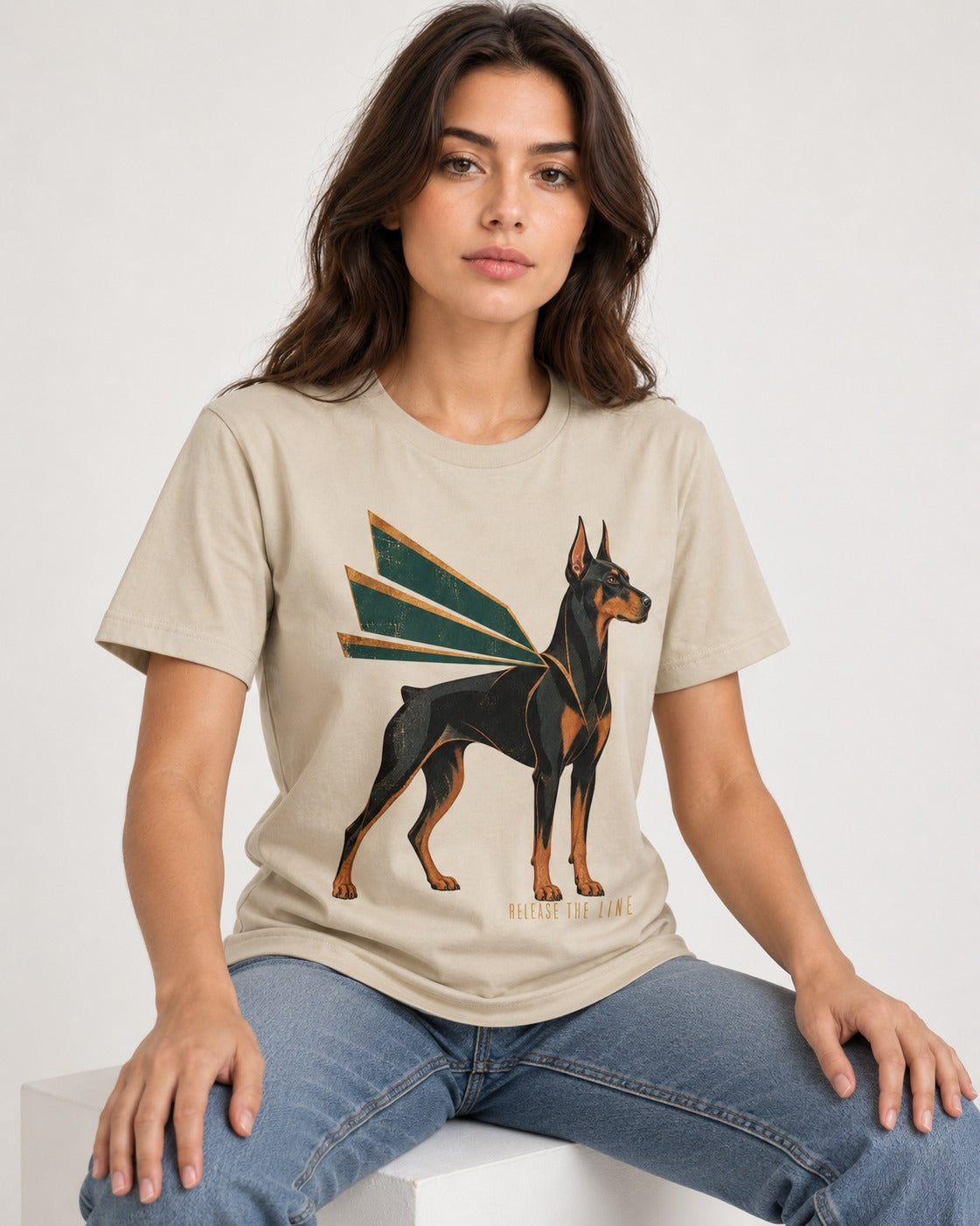 Release the Doberman Line T-Shirt in Sand, worn by a seated model