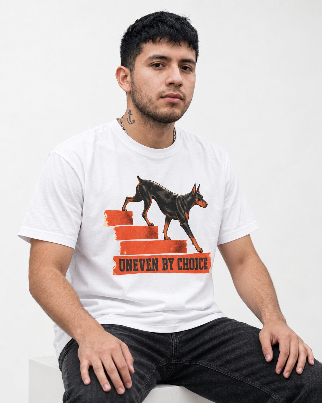 Doberman Uneven by Choice Stair Graphic T-Shirt in White, worn by a seated model