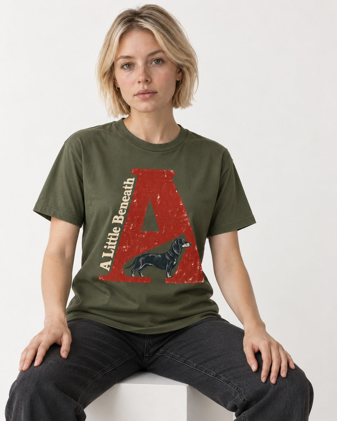 Dachshund A Little Beneath Monumental Letter Graphic T-Shirt in Heather Military Green, worn by a seated model