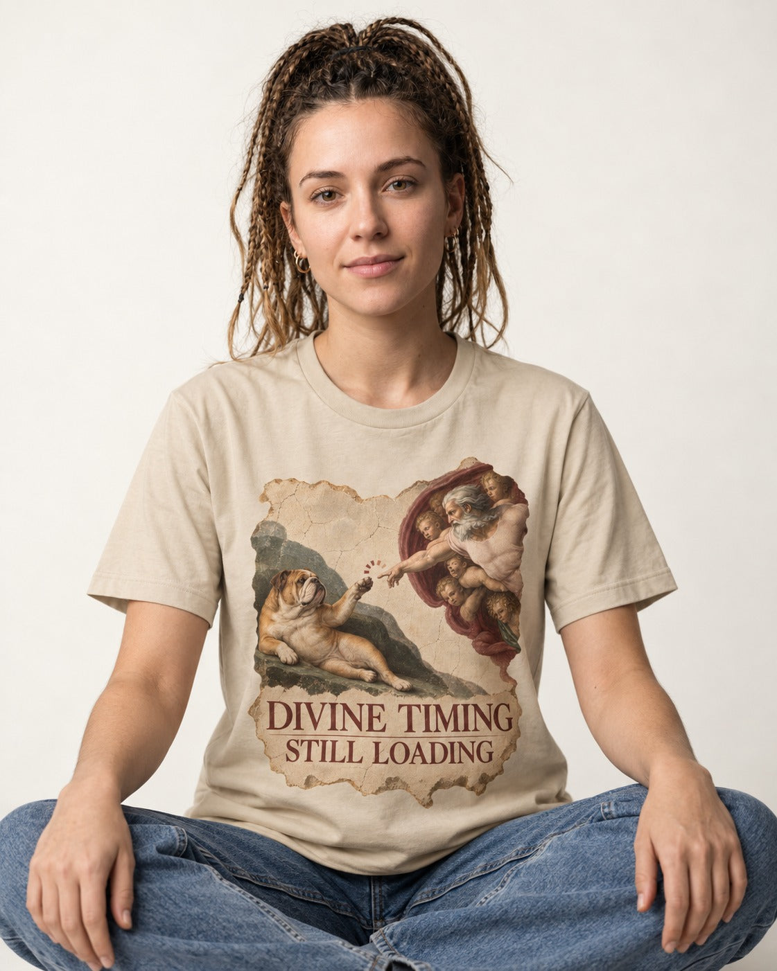 English Bulldog Divine Timing Still Loading T-Shirt in Sand, worn by a seated model