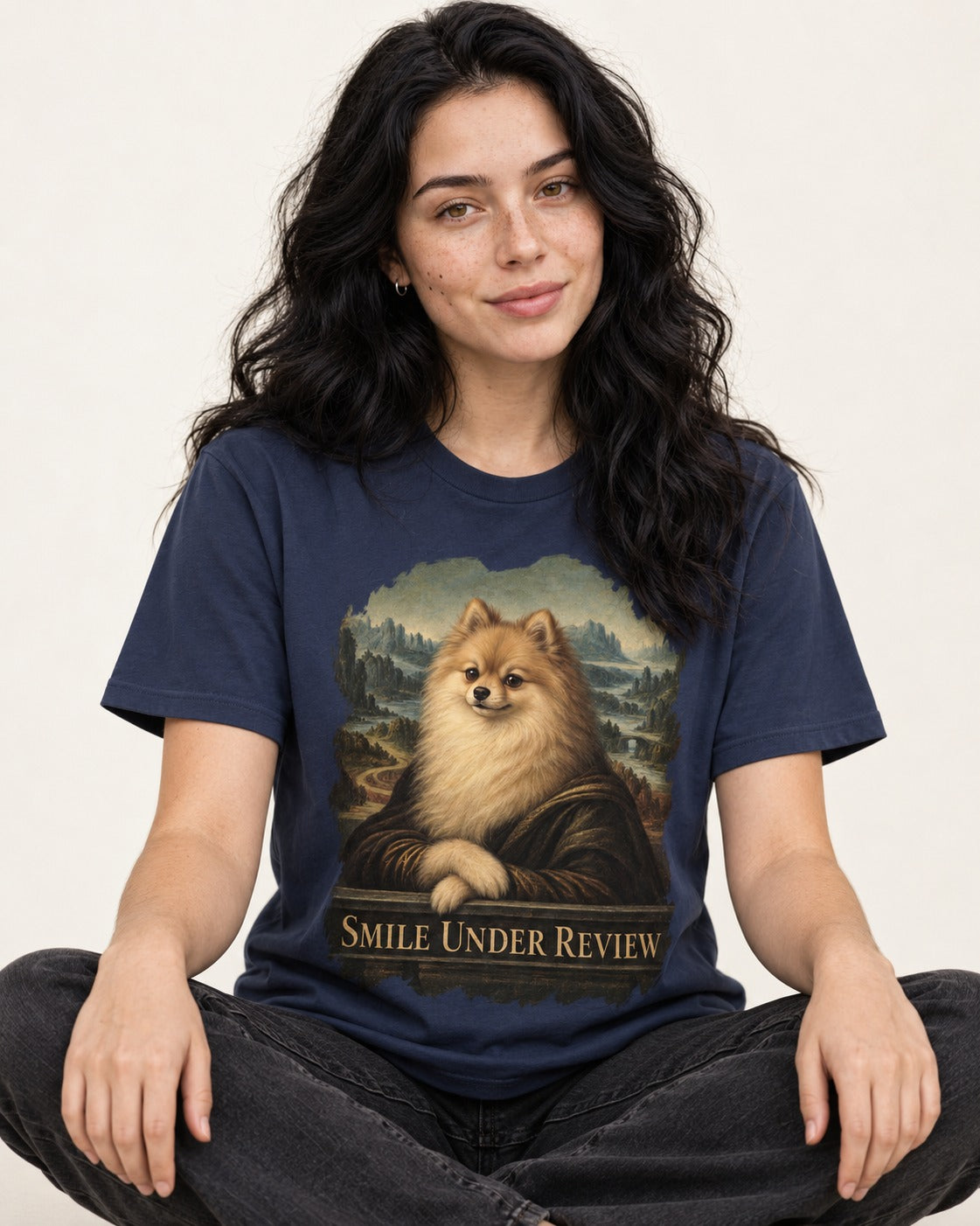 Pomeranian Smile Under Review Renaissance Portrait Graphic T-Shirt in Navy, worn by a seated model