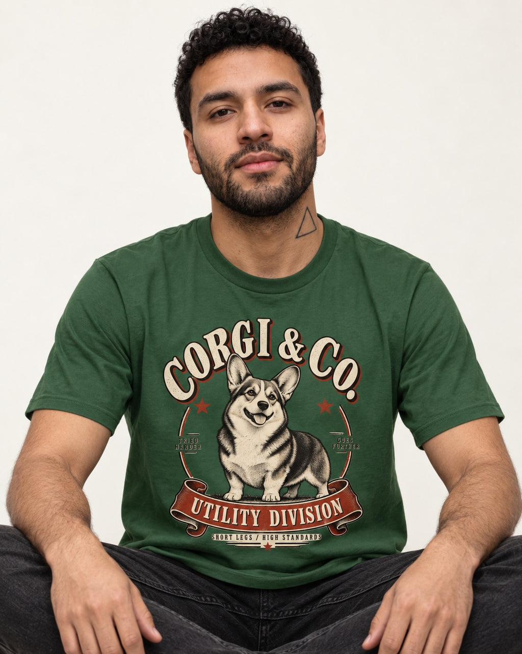 Corgi's High Standards T-Shirt in Forest Green, worn by a seated model
