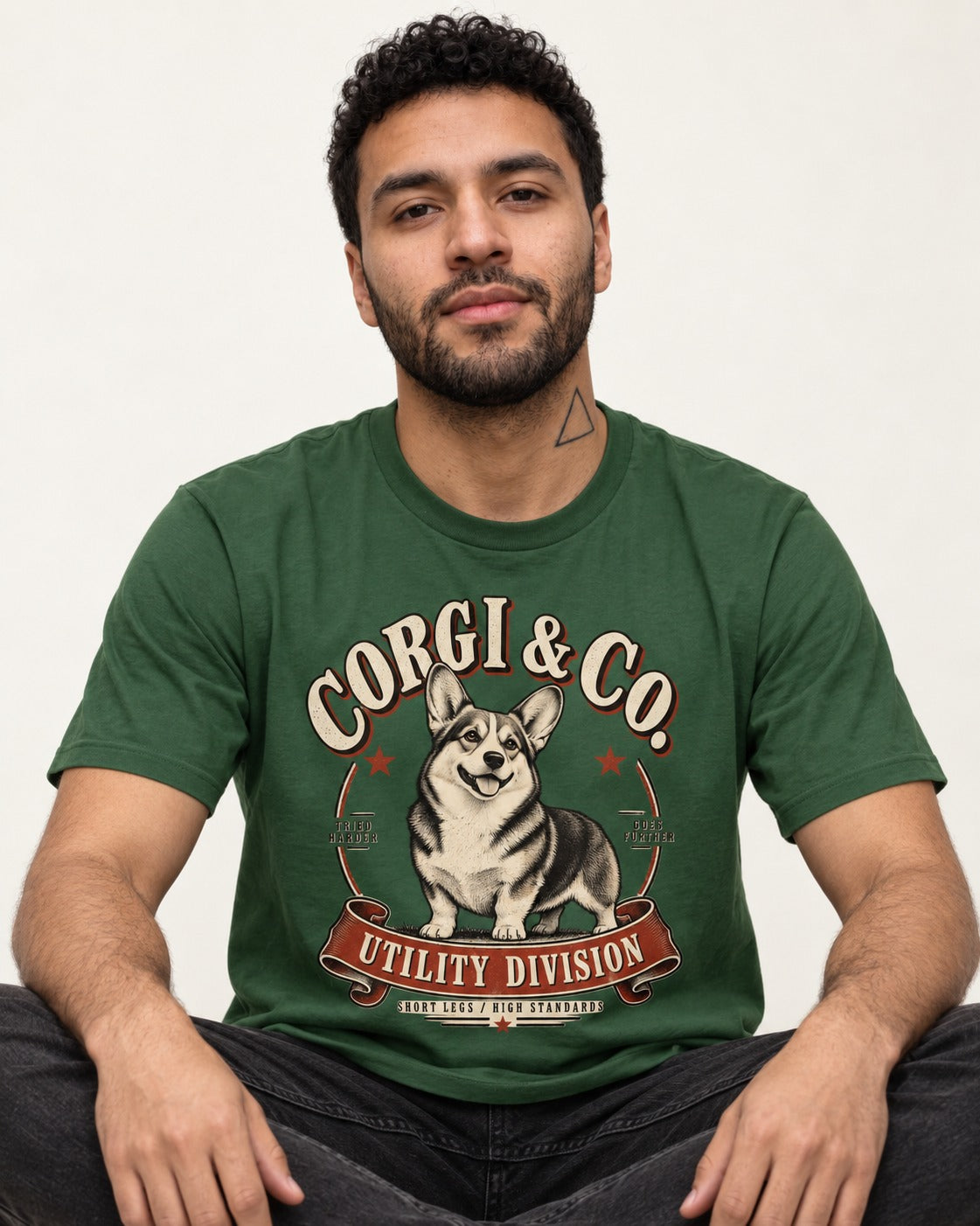 Corgi's High Standards T-Shirt in Forest Green, worn by a seated model