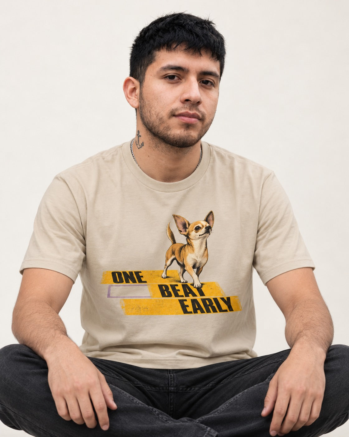 One Beat Early Chihuahua T-Shirt in Sand, worn by a seated model
