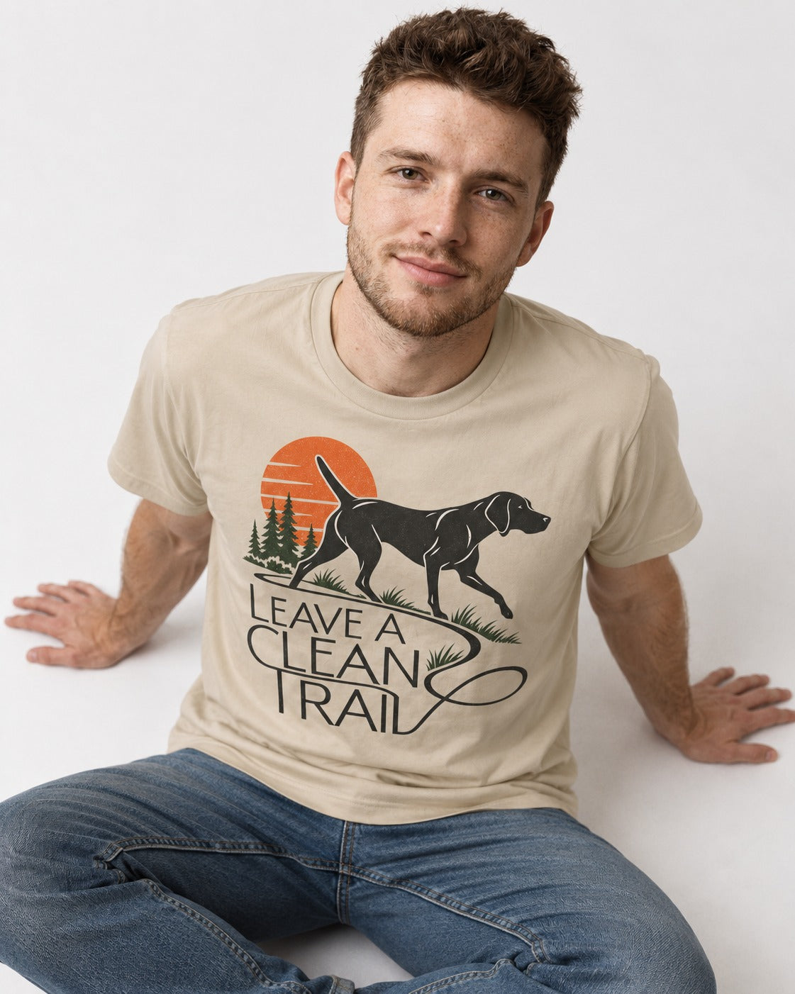Leave a Clean Trail German Shorthaired Pointer T-Shirt in Sand, worn by a seated model