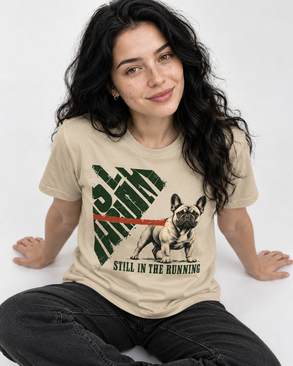 Frenchie Still in the Running T-Shirt in Sand, worn by a seated model
