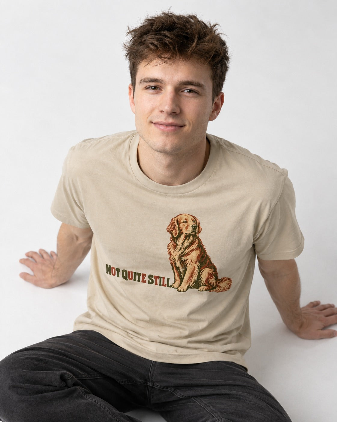 Golden Retriever Not Quite Still T-Shirt in Sand, worn by a seated model