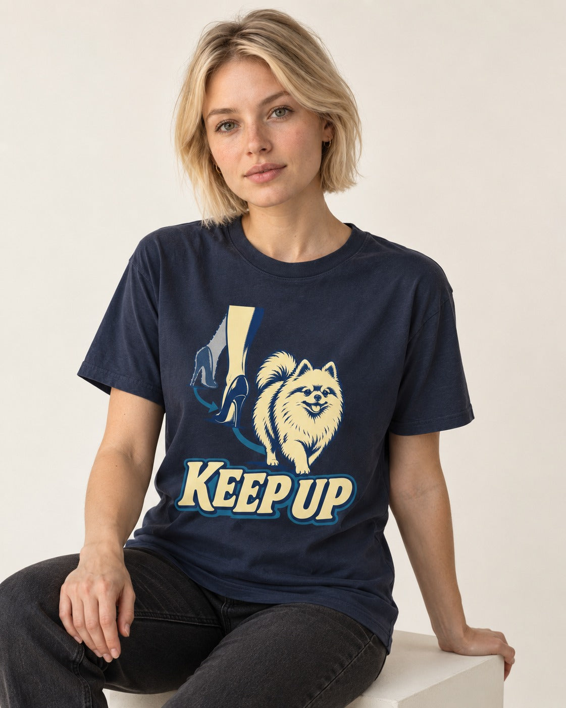 Pomeranian Keep Up High Heel Chase Graphic T-Shirt in Navy, worn by a seated model