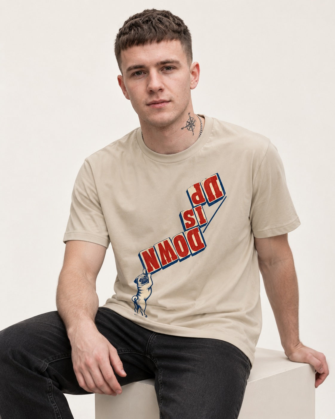 Down Is Up Pug T-Shirt in Sand, worn by a seated model