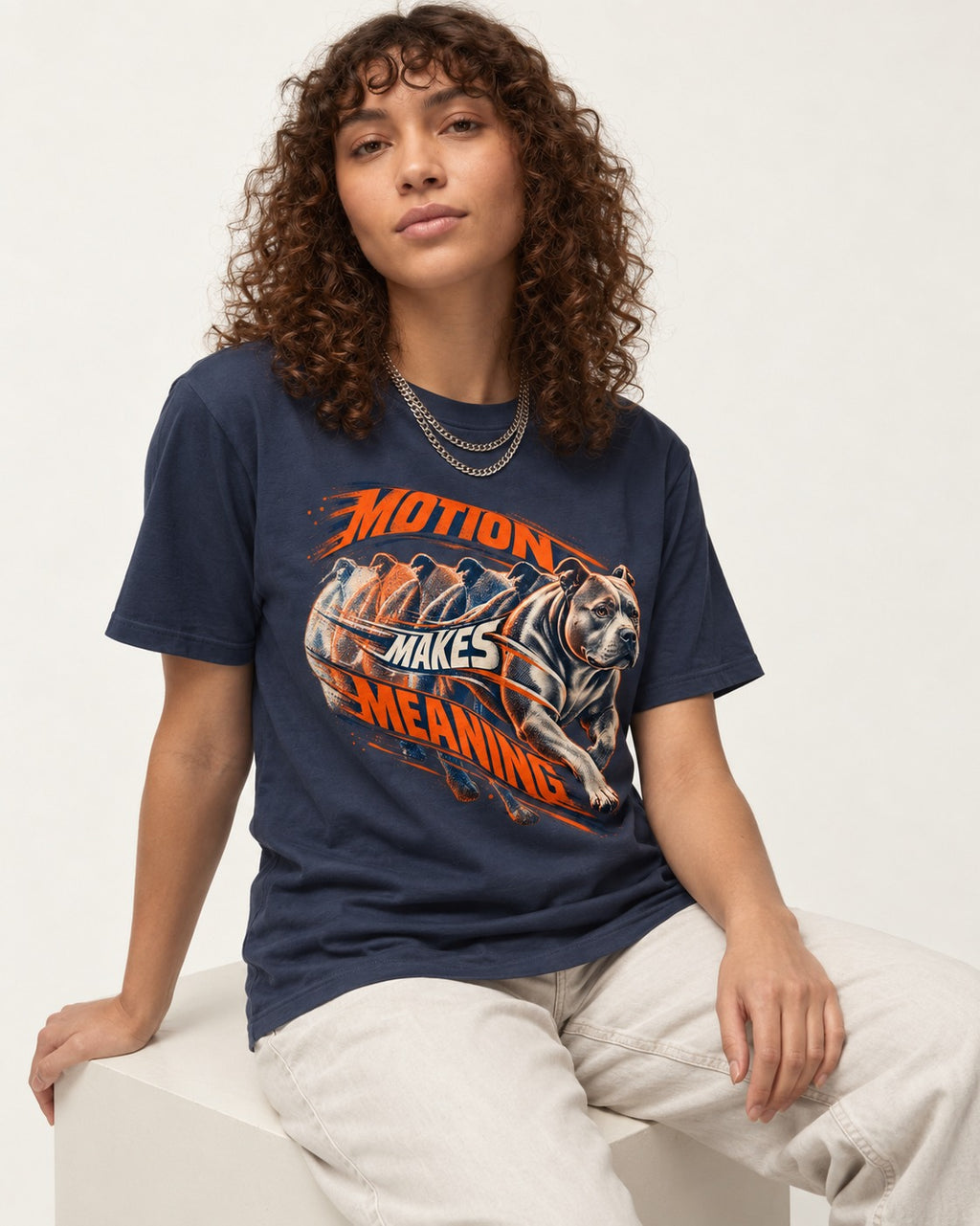 Pitbull Motion Makes Meaning Running Dog Graphic T-Shirt in Navy, worn by a seated model