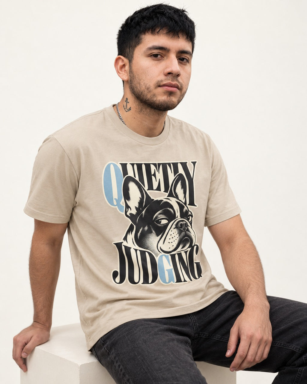 Quietly Judging Frenchie T-Shirt in Sand, worn by a seated model