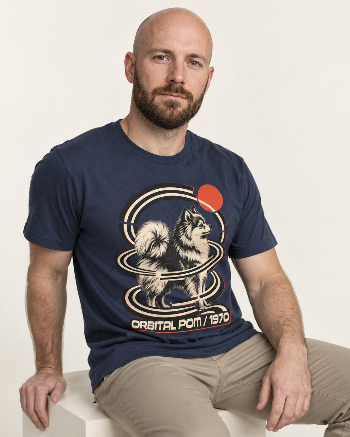 Pomeranian Orbital Pom 1970 Space Age Graphic T-Shirt in Navy, worn by a seated model