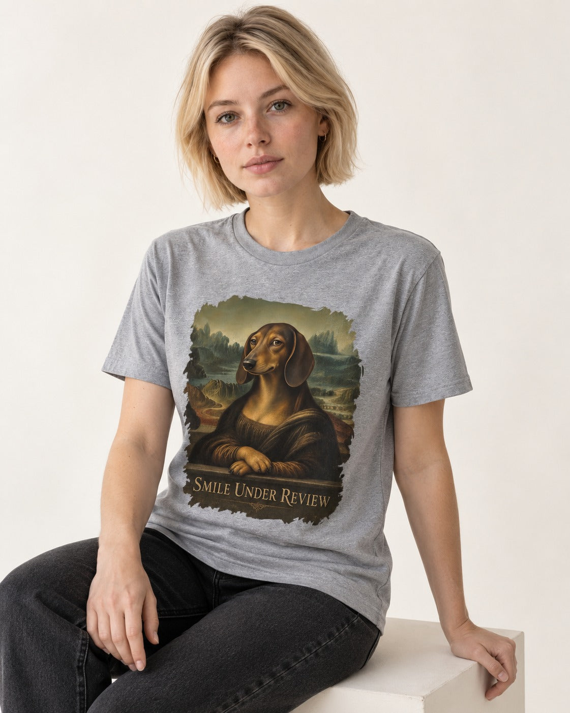 Dachshund Smile Under Review Mona Lisa Graphic T-Shirt in Sport Grey, worn by a seated model