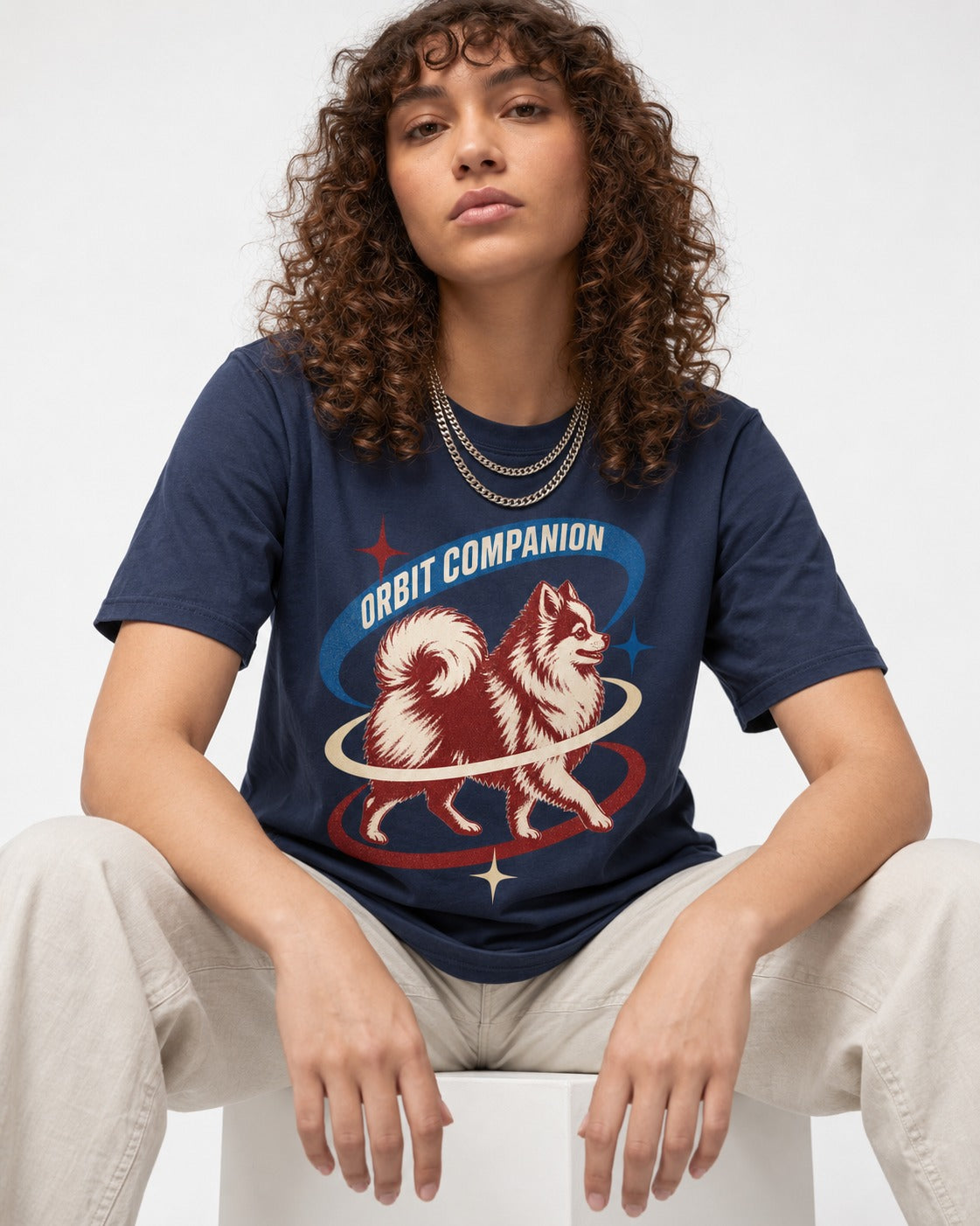 Pomeranian Orbit Companion Retro Space Graphic T-Shirt in Navy, worn by a seated model