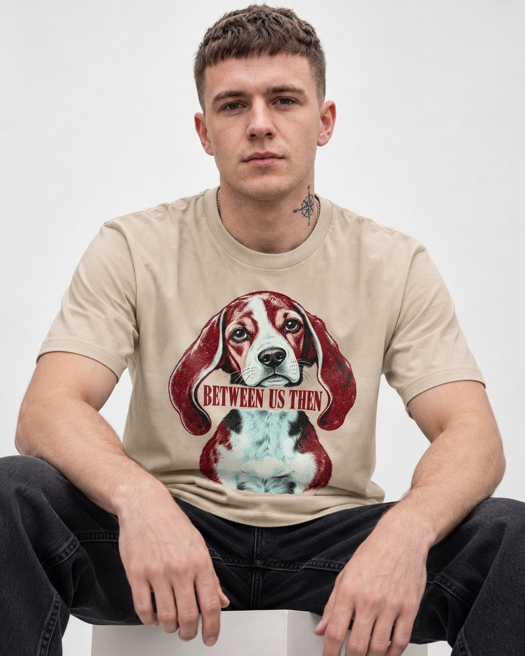 Beagle Between Us Then T-Shirt in Sand, worn by a seated model