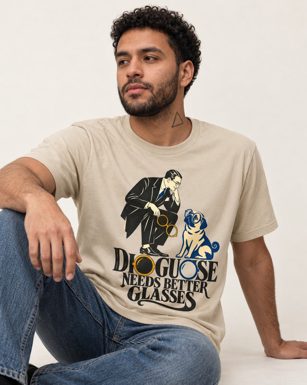 Pug Needs Better Glasses T-Shirt in Sand, worn by a seated model