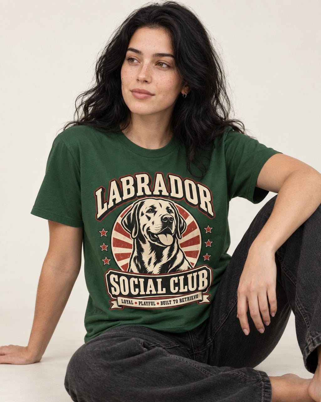 Labrador Retriever Social Club Loyal Playful Built to Retrieve Badge Graphic T-Shirt in Forest Green, worn by a seated model