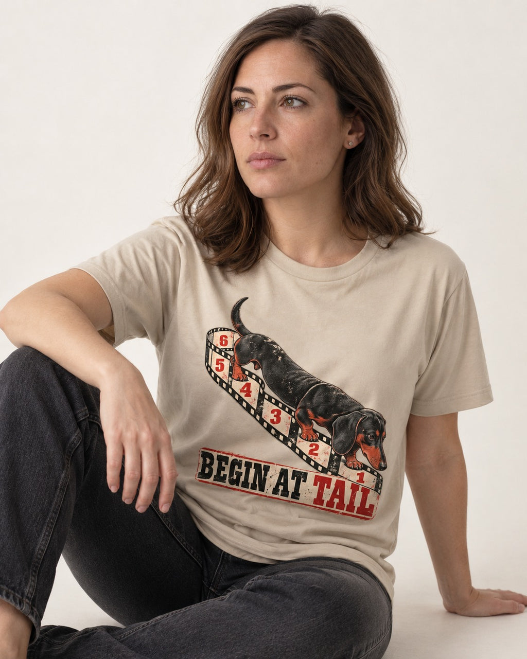 Begin at Tail Dachshund T-Shirt in Sand, worn by a seated model