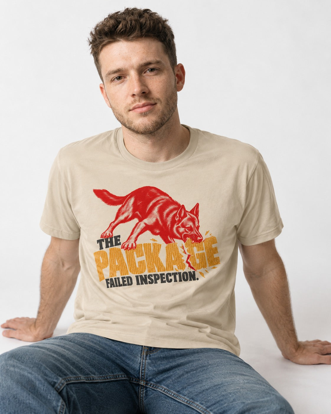 The Package Failed Inspection German Shepherd Dog T-Shirt in Sand, worn by a seated model