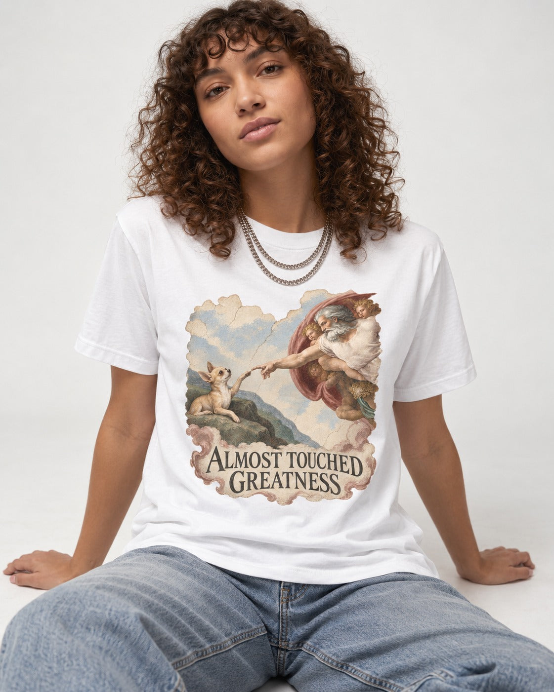 Chihuahua Almost Touched Greatness Renaissance Parody T-Shirt in White, worn by a seated model