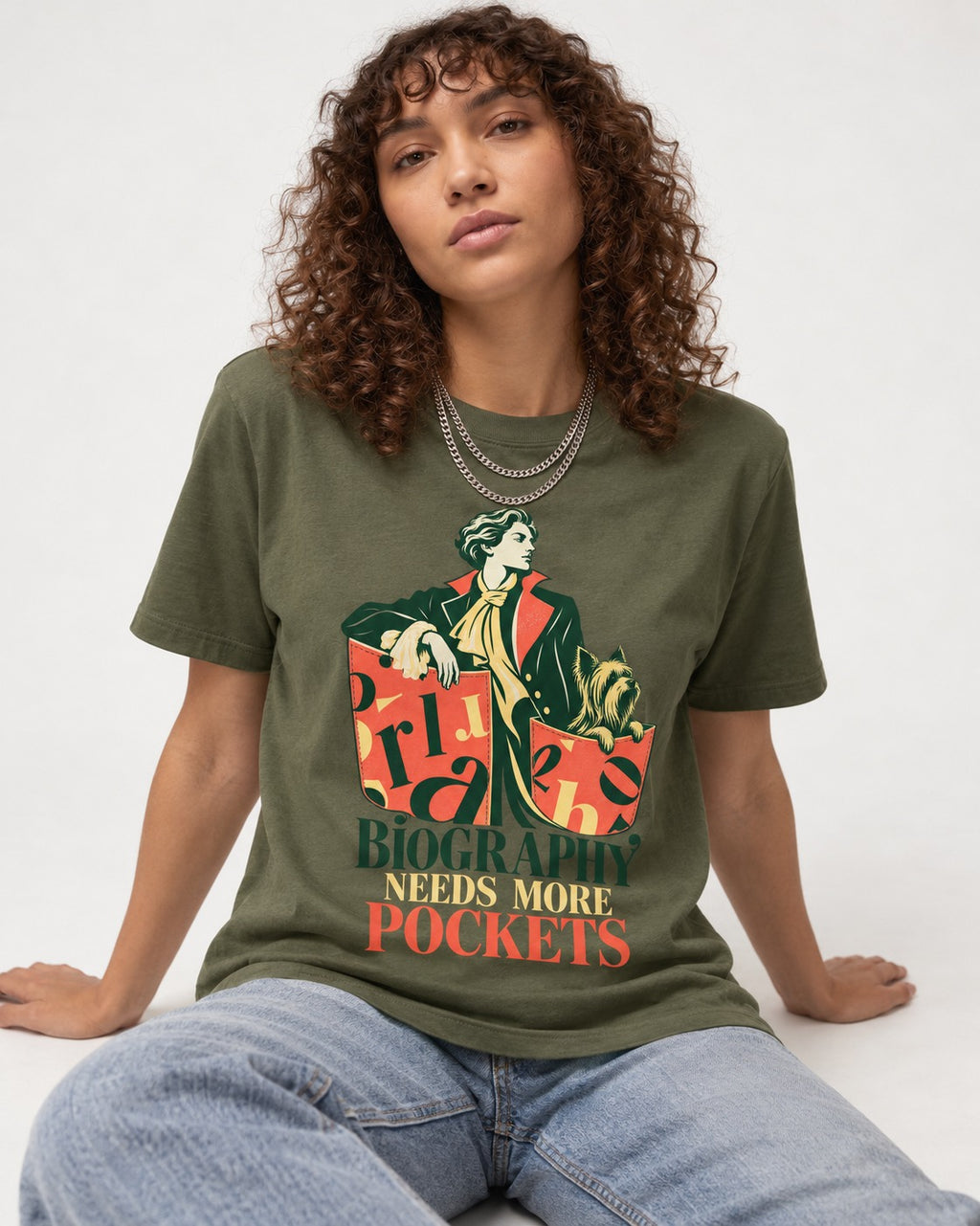 Yorkshire Terrier Biography Needs More Pockets Literary Portrait Graphic T-Shirt in Heather Military Green, worn by a seated model