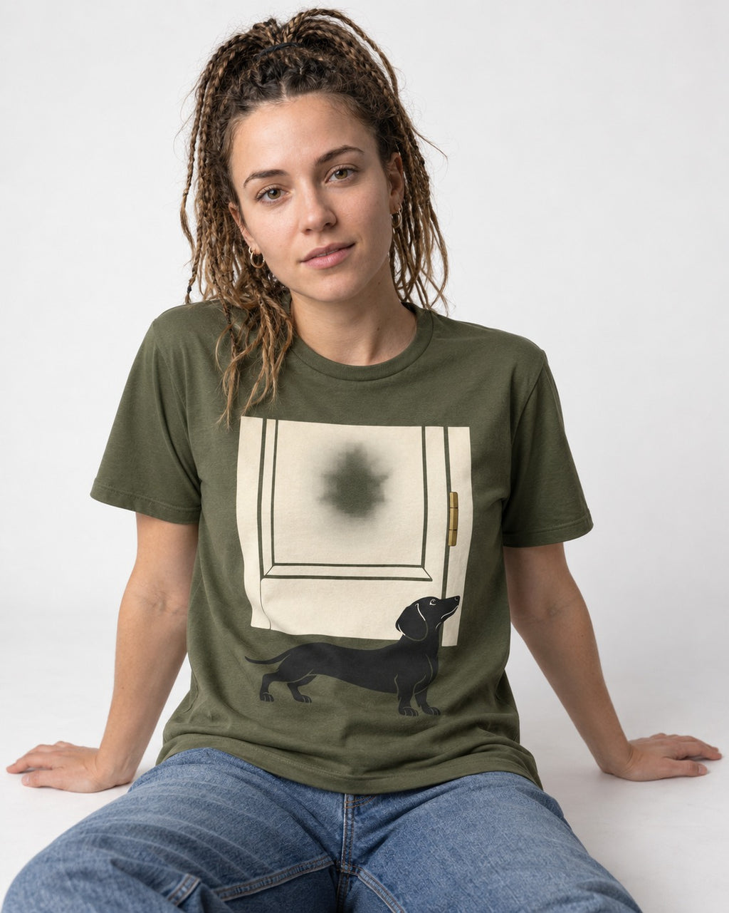 Dachshund Frosted Door Sentinel Graphic T-Shirt in Heather Military Green, worn by a seated model
