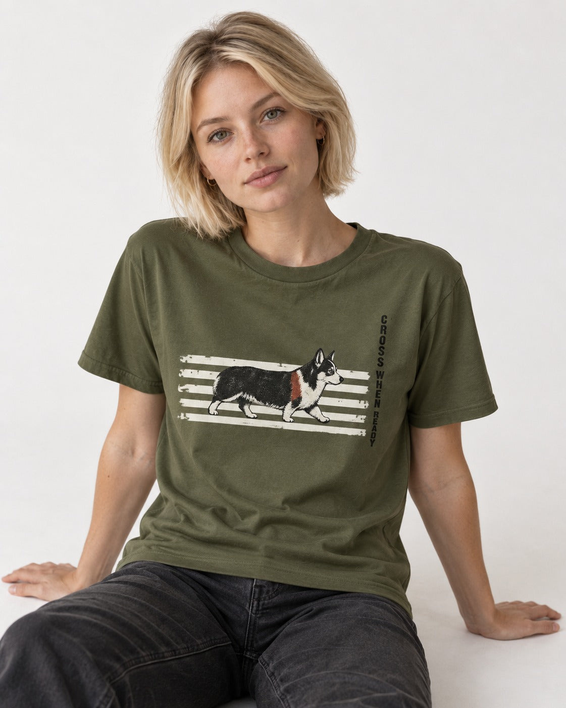 Corgi Cross When Ready Crossing Bars Graphic T-Shirt in Heather Military Green, worn by a seated model